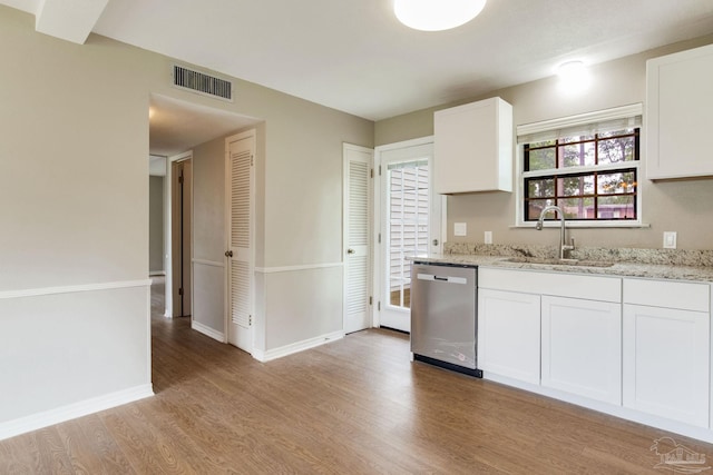 kitchen featuring stainless steel dishwasher, a sink, light wood finished floors, white cabinetry, and light stone countertops