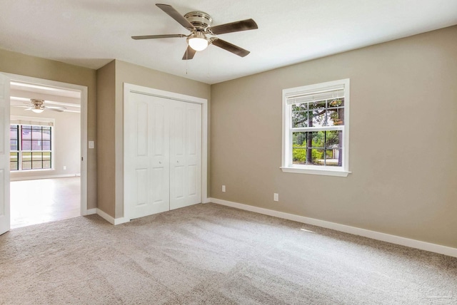 unfurnished bedroom featuring carpet flooring, baseboards, a closet, and a ceiling fan