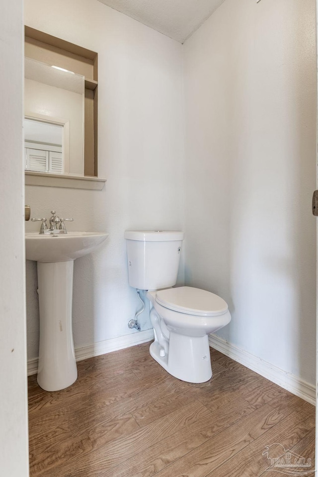 bathroom featuring toilet, wood finished floors, and baseboards