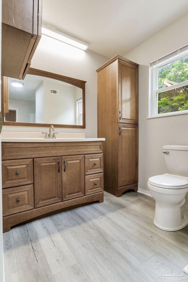 bathroom with wood finished floors, toilet, vanity, and baseboards
