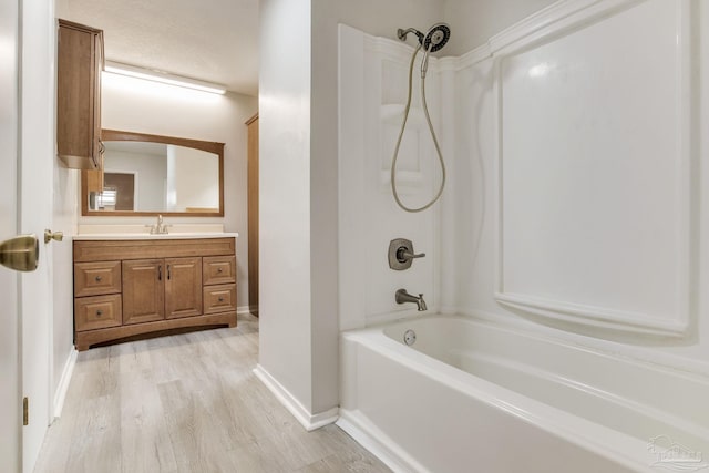 bathroom with shower / washtub combination, wood finished floors, baseboards, and vanity