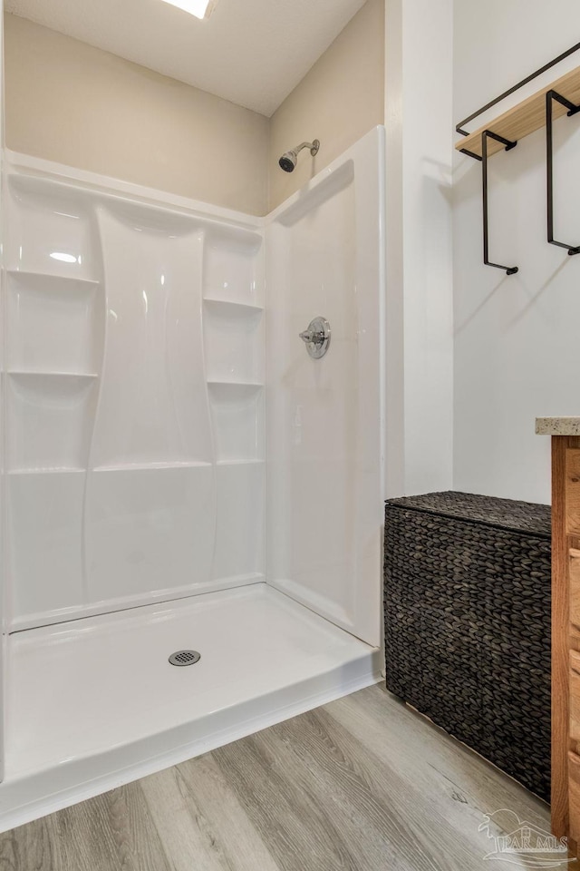 bathroom with wood finished floors and a walk in shower
