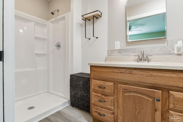 full bathroom with a shower stall, a ceiling fan, vanity, and wood finished floors
