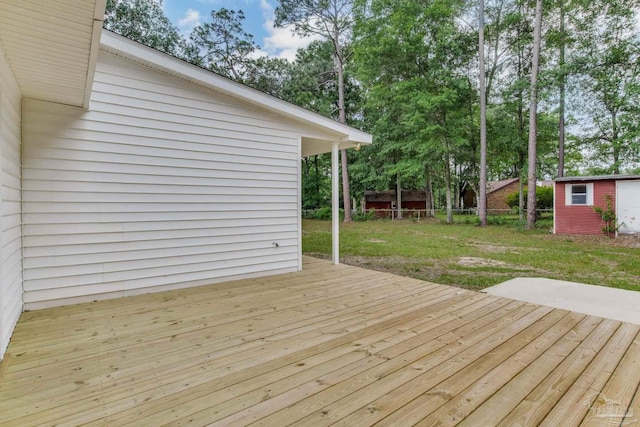 wooden deck featuring an outdoor structure and a lawn