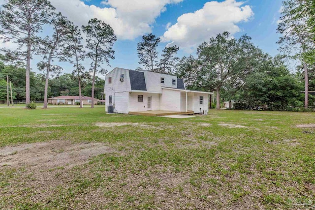 back of house with a gambrel roof, a lawn, roof with shingles, a deck, and central AC