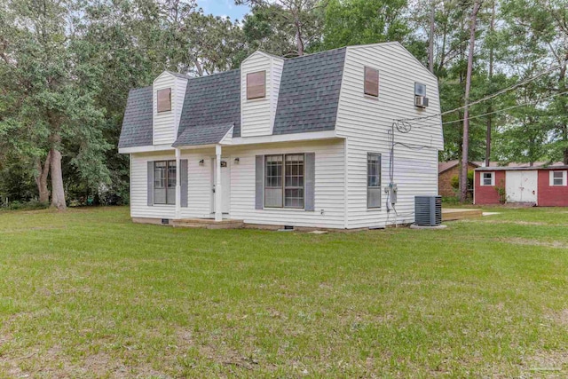 colonial inspired home with roof with shingles, a gambrel roof, a front yard, and central AC