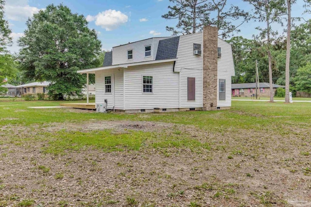 back of house with a chimney, a yard, a gambrel roof, and a shingled roof