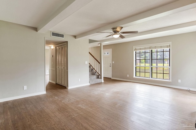 unfurnished living room with beam ceiling, wood finished floors, stairs, ceiling fan, and baseboards