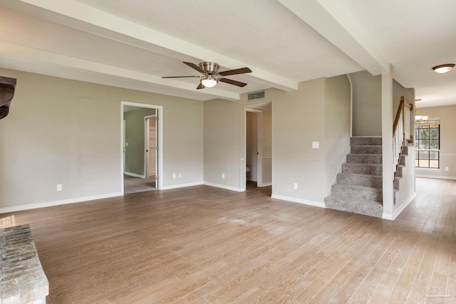 unfurnished living room featuring light wood finished floors, baseboards, a ceiling fan, stairs, and beamed ceiling