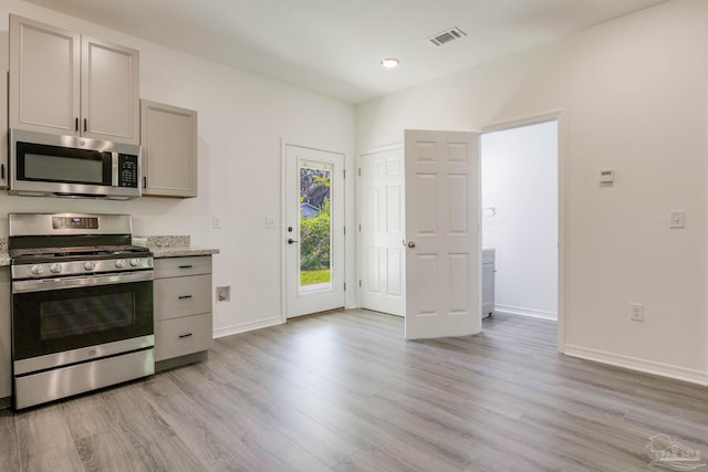 kitchen featuring light stone countertops, stainless steel appliances, light hardwood / wood-style floors, and gray cabinetry