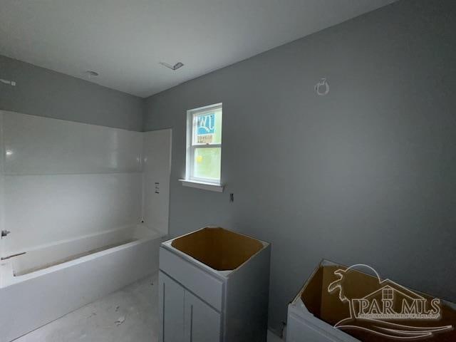 bathroom with concrete flooring and a tub