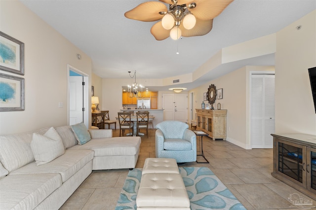 tiled living room with ceiling fan with notable chandelier