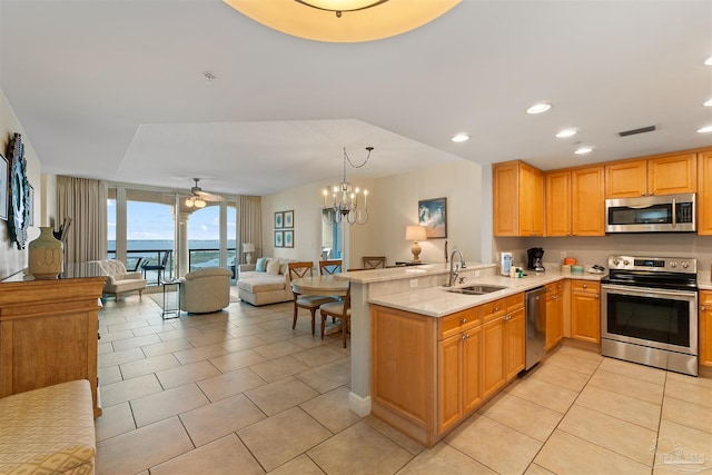 kitchen with kitchen peninsula, stainless steel appliances, a water view, and sink