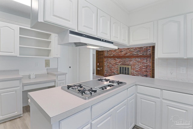 20 Magnolia Ave, Shalimar, FL 32579 - kitchen featuring under cabinet range hood, stainless steel gas cooktop, a peninsula, white cabinets, and crown molding