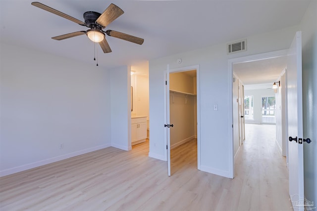 unfurnished bedroom with a spacious closet, light hardwood / wood-style flooring, ceiling fan, and a closet