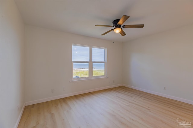 empty room featuring a water view, ceiling fan, and light hardwood / wood-style floors