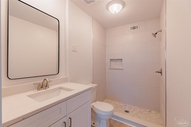 bathroom featuring vanity, toilet, and a tile shower