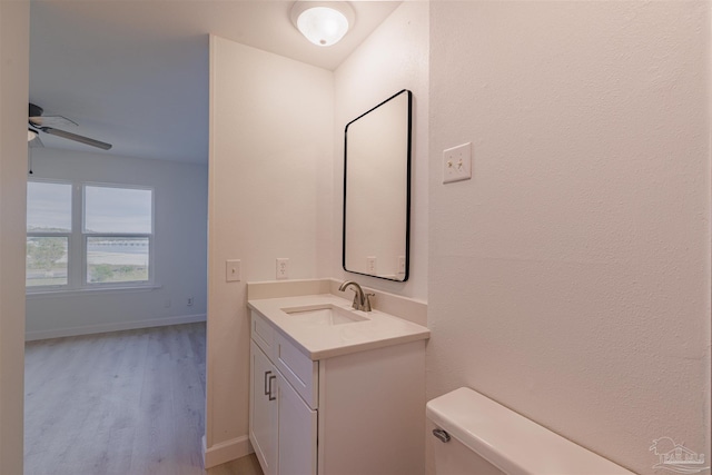 bathroom featuring vanity, hardwood / wood-style floors, ceiling fan, and toilet