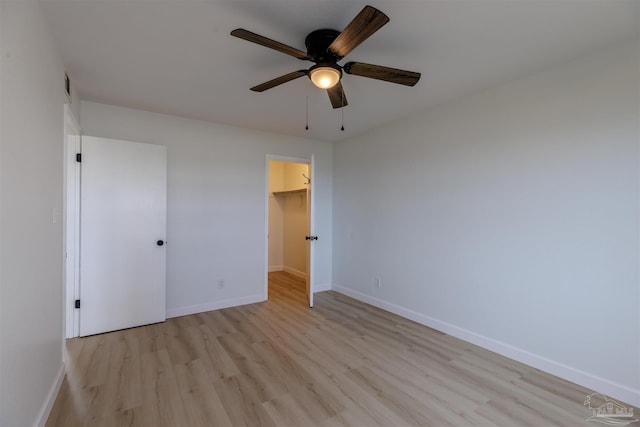 unfurnished bedroom with a walk in closet, light hardwood / wood-style flooring, a closet, and ceiling fan