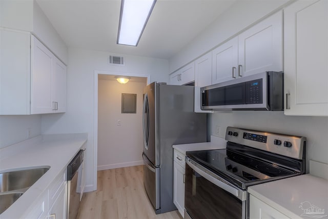 kitchen with stainless steel appliances, sink, white cabinets, and light hardwood / wood-style floors