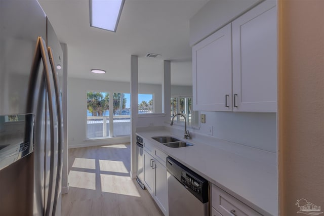 kitchen with white cabinetry, sink, stainless steel appliances, and light hardwood / wood-style floors