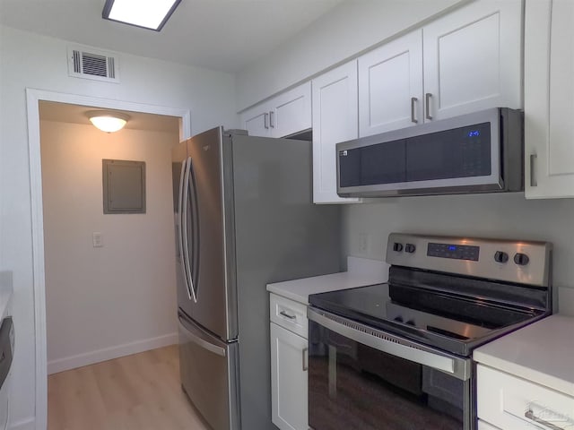 kitchen featuring white cabinetry, appliances with stainless steel finishes, electric panel, and light hardwood / wood-style flooring