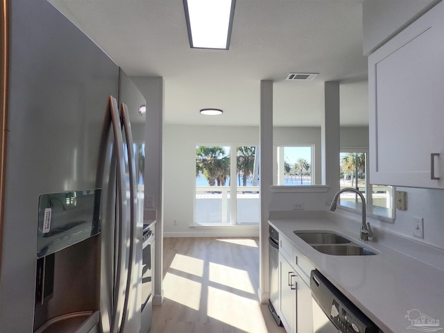 kitchen with white cabinetry, sink, stainless steel appliances, and light hardwood / wood-style floors