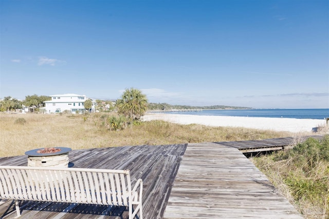 view of dock featuring a water view, a beach view, and a fire pit