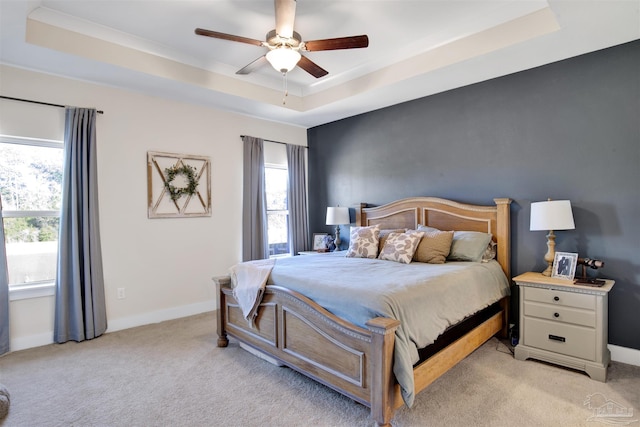 bedroom featuring ceiling fan, a raised ceiling, and multiple windows