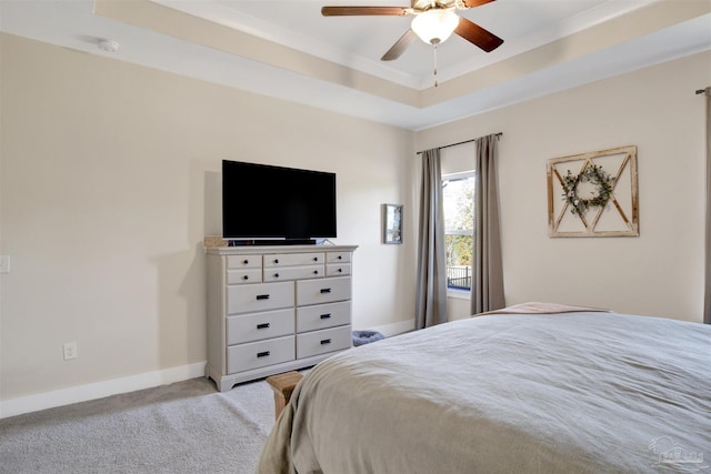 carpeted bedroom featuring ceiling fan and a tray ceiling