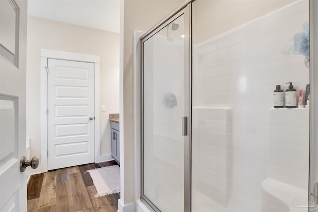 bathroom with a shower with shower door, hardwood / wood-style floors, and vanity