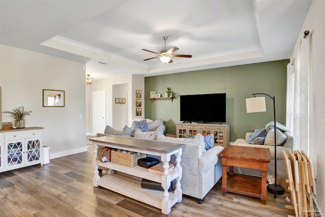 living room with a raised ceiling, ceiling fan, and hardwood / wood-style floors