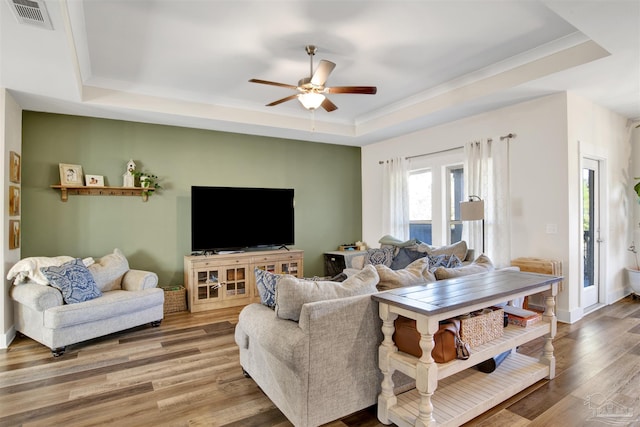 living room featuring ceiling fan, hardwood / wood-style floors, and a raised ceiling