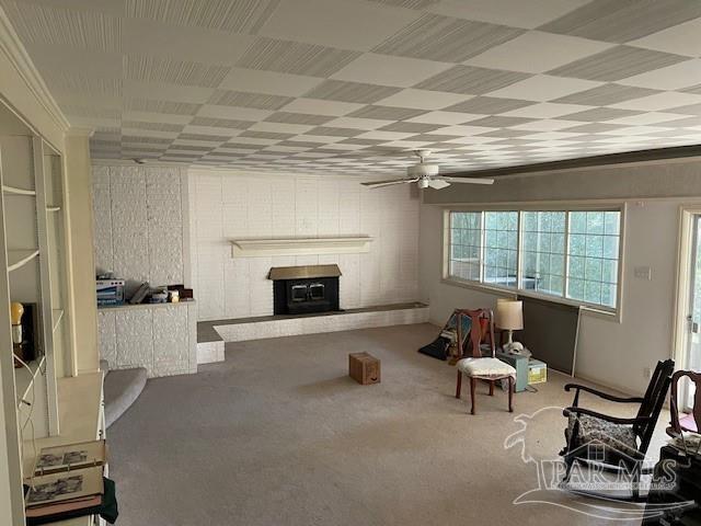 sitting room with carpet, a brick fireplace, ceiling fan, and ornamental molding