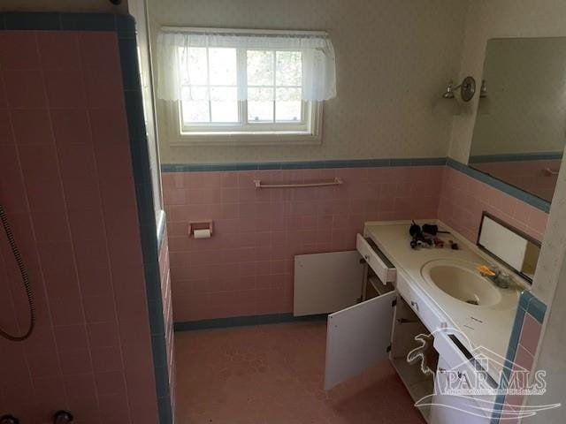 bathroom with a shower, vanity, and tile walls