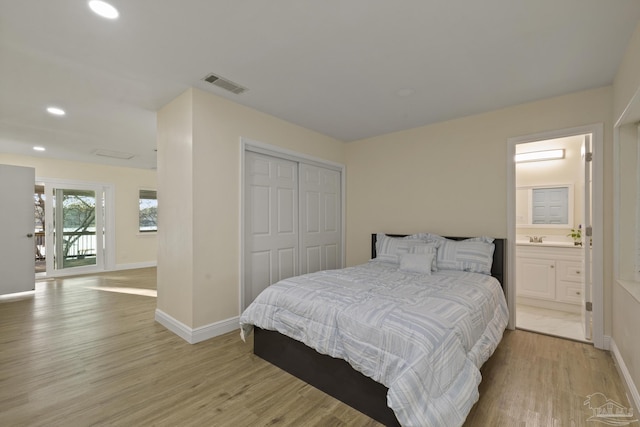 bedroom featuring sink, ensuite bath, a closet, and light wood-type flooring