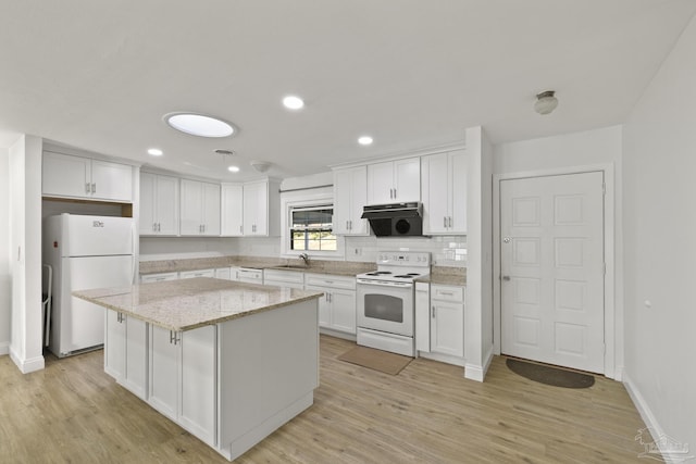 kitchen featuring light stone counters, white appliances, white cabinets, and a kitchen island