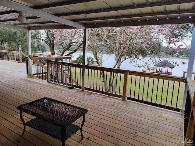 deck with a water view and a lawn