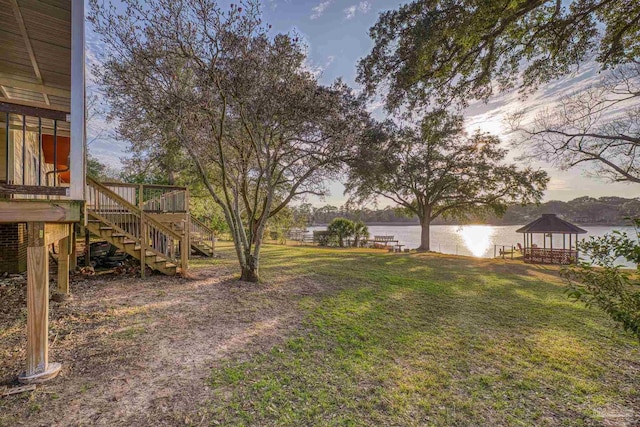 yard at dusk with a gazebo and a water view