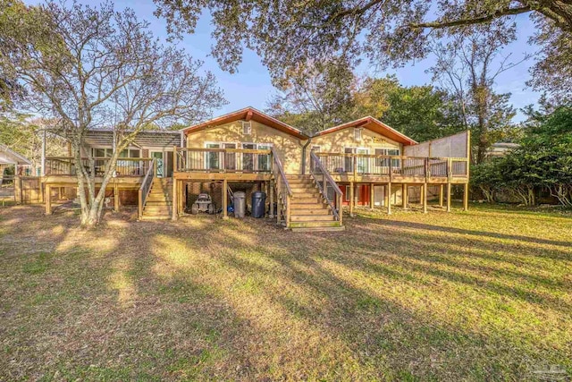 rear view of property featuring a wooden deck and a lawn