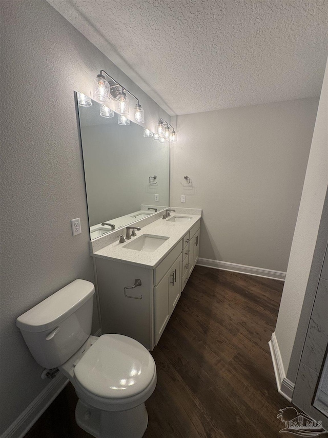 bathroom with a textured ceiling, wood finished floors, a sink, and baseboards