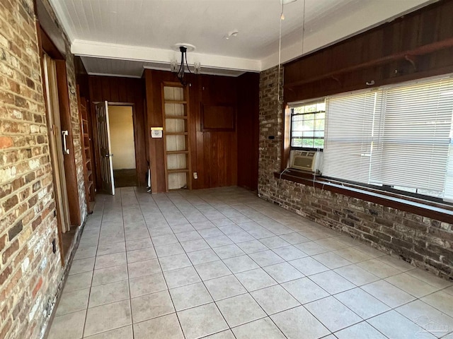 spare room featuring wood walls, cooling unit, light tile patterned floors, and brick wall