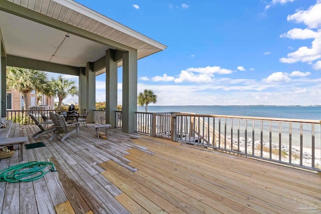 wooden deck featuring a water view and a beach view