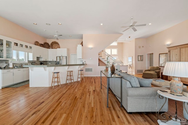 unfurnished living room featuring ceiling fan, sink, and light hardwood / wood-style floors