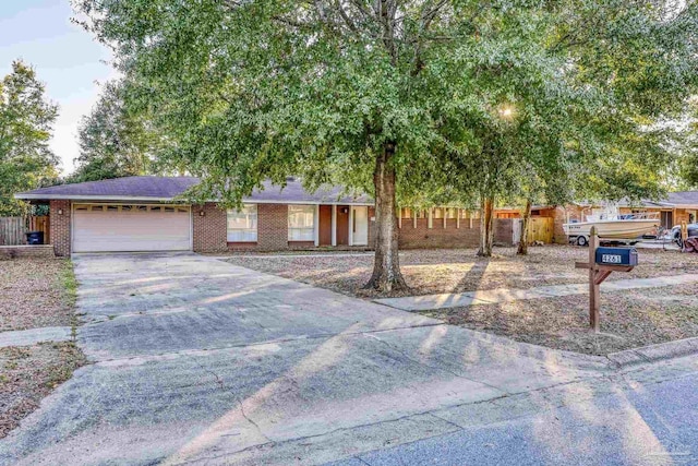 single story home featuring driveway, brick siding, an attached garage, and fence