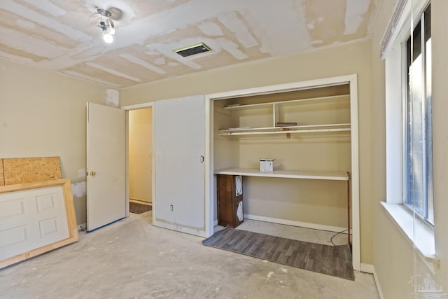 unfurnished bedroom featuring a closet, visible vents, baseboards, and unfinished concrete floors