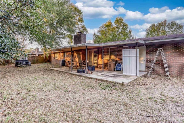 rear view of property with a patio area, brick siding, a chimney, and fence