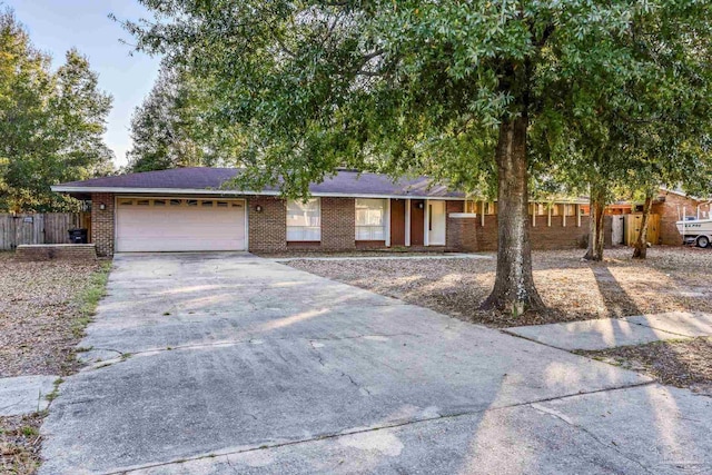 ranch-style home featuring a garage, fence, concrete driveway, and brick siding