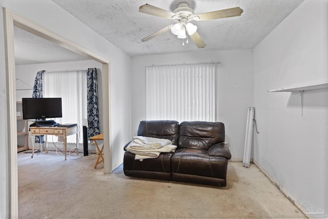 living area featuring a textured ceiling, a ceiling fan, and concrete flooring