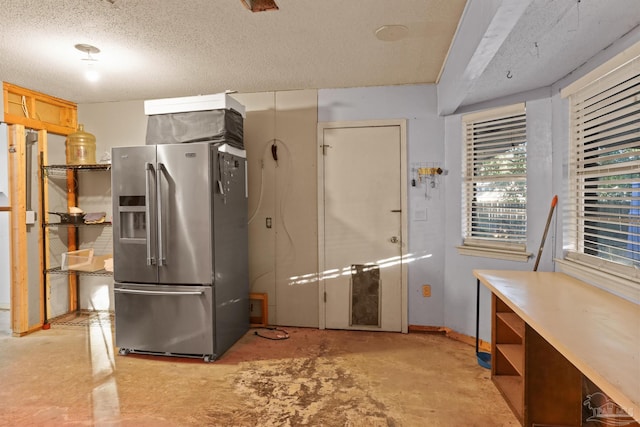 kitchen with unfinished concrete floors, a textured ceiling, and stainless steel fridge with ice dispenser